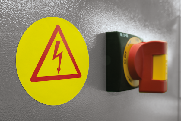 Gelbes, rundes Warnschild an der Elektroanlage