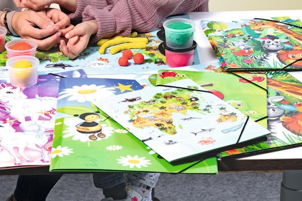 Schreibtisch mit verschiedenen bunten Sammelmappen, die mit Kindermotiven gestaltet sind.