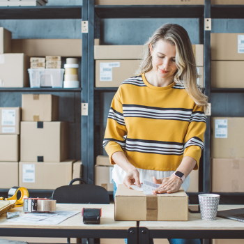 Frau, die ein Etikett auf ein Paket aufklebt.