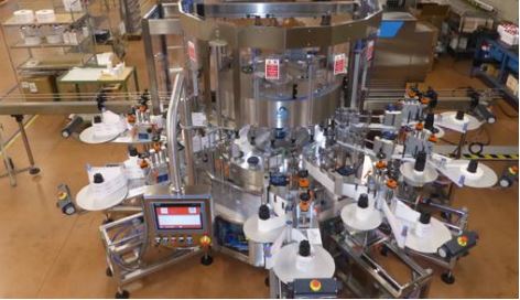 Automatische Etikettiermaschine mit mehreren Stationen, ausgestattet mit einem Bedienfeld und zahlreichen Etikettierarmen.