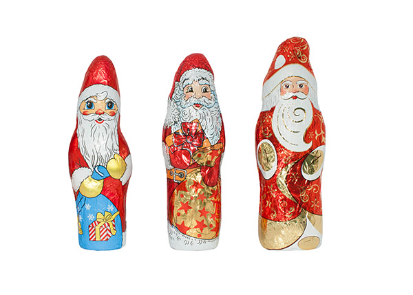 Drei dekorative Weihnachtsmänner aus Schokolade, jeweils in unterschiedlichen Designs und Farben, stehen nebeneinander.