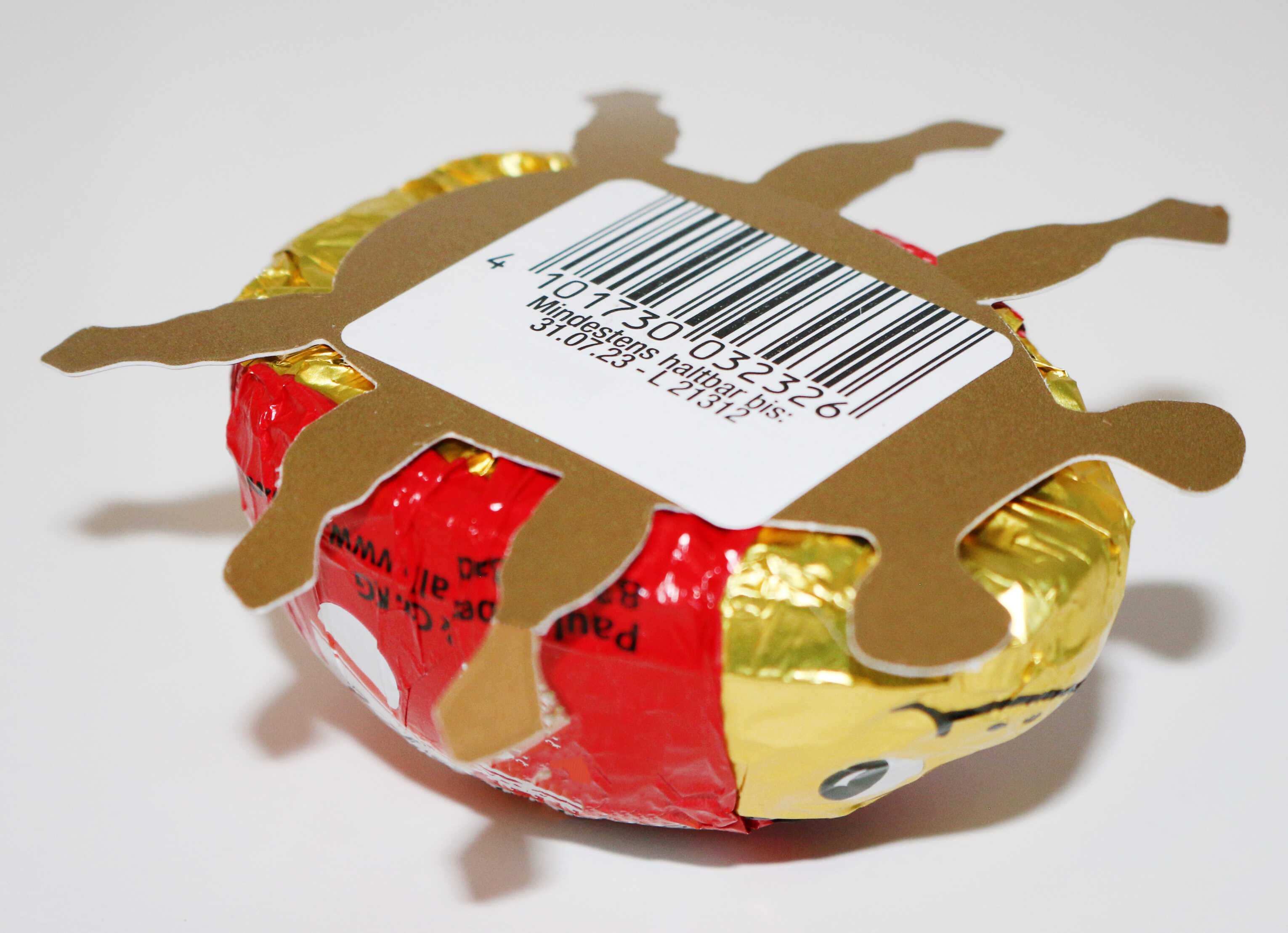 Runder Schokoladenbonbon mit goldener und roter Folie, dekoriert mit einer Pappfigur in Form einer Sonne und einem Barcode.