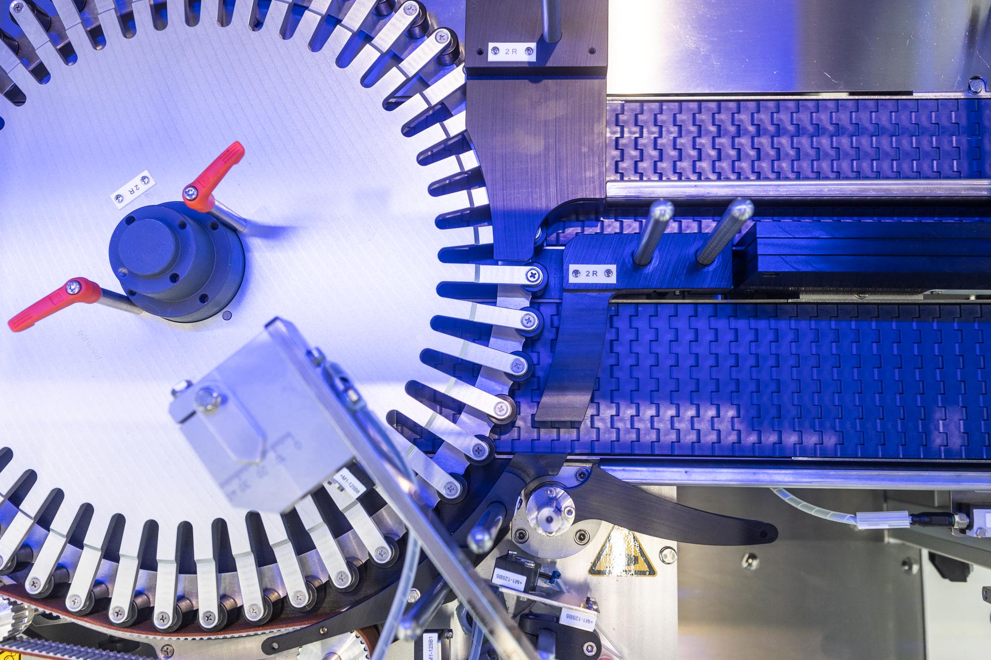 Maschine mit rotierenden Teilen und Förderband, die für industrielle Prozesse verwendet wird. Technische Komponenten sind sichtbar.