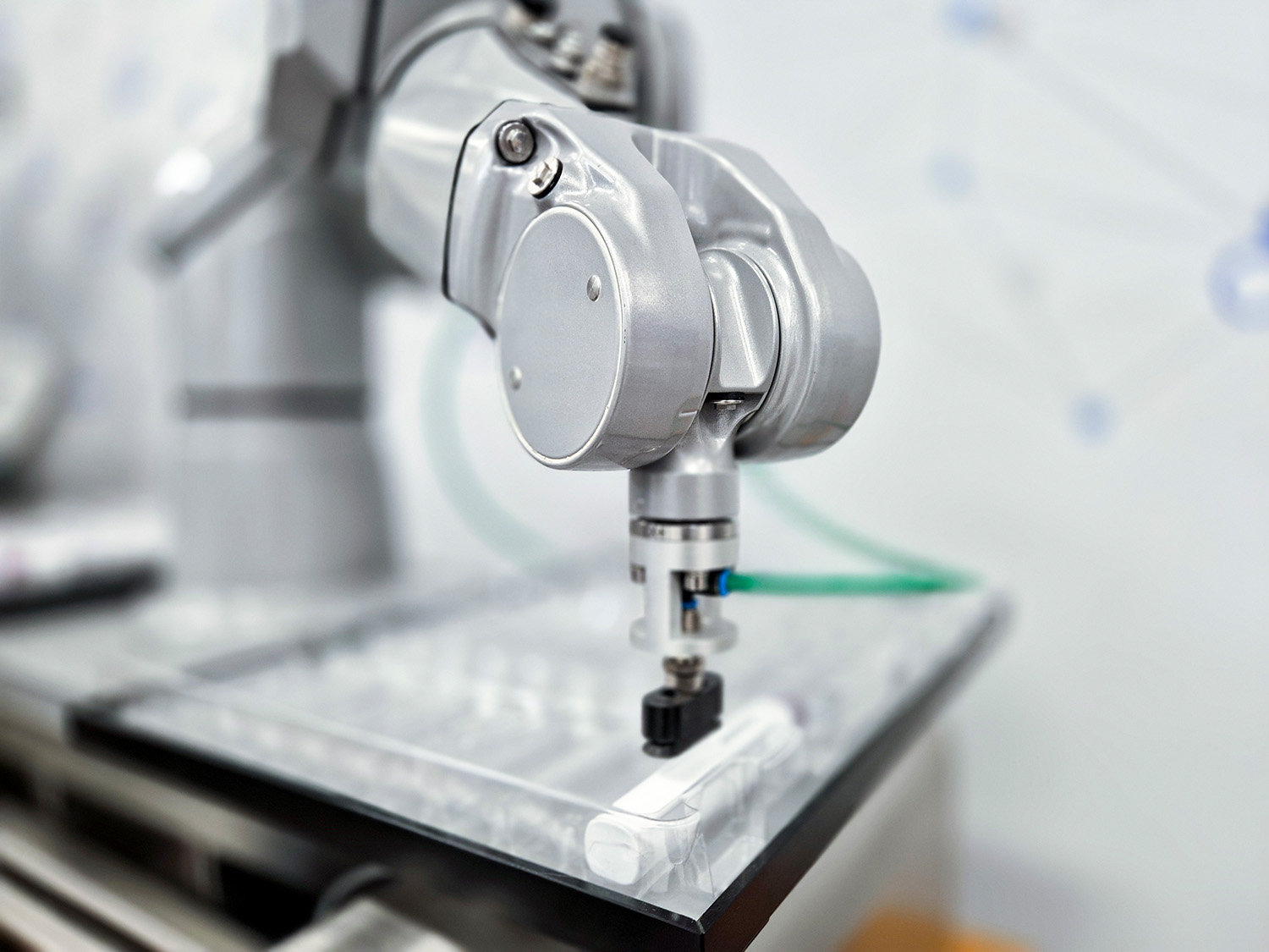 Industrieroboterarm mit Greifer, der auf einer durchsichtigen Fläche platziert ist, bereit, ein Objekt zu greifen.