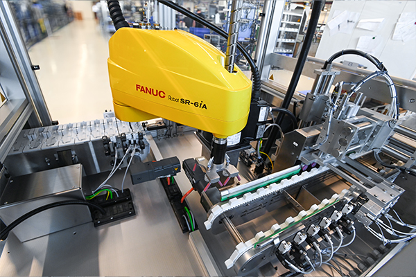 Industrieroboter von FANUC, Modell R-6iA, in einer automatisierten Produktionsumgebung, ausgestattet mit verschiedenen Komponenten zur Montage.