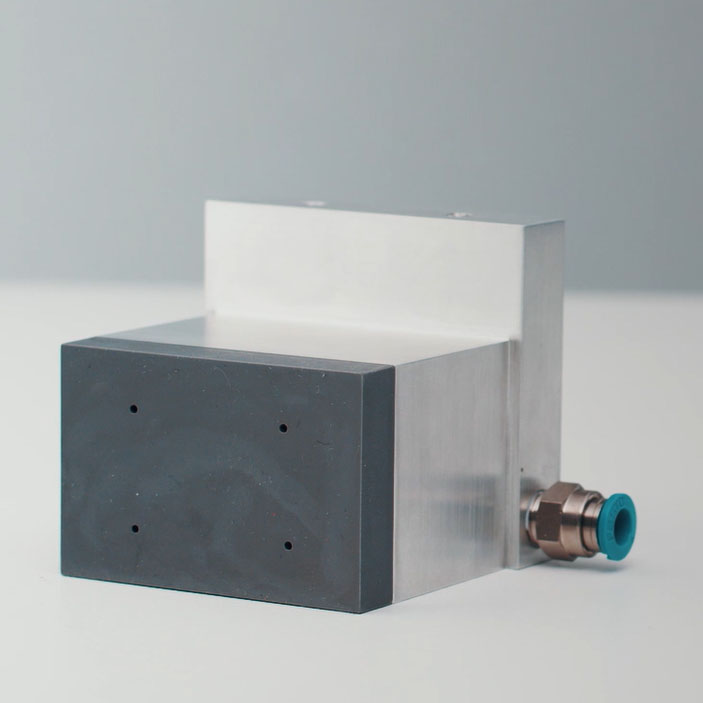 Ein rechteckiges Gerät mit einer metallischen Oberfläche und einem schwarzen Kunststoffblock, ausgestattet mit einem Anschluss.