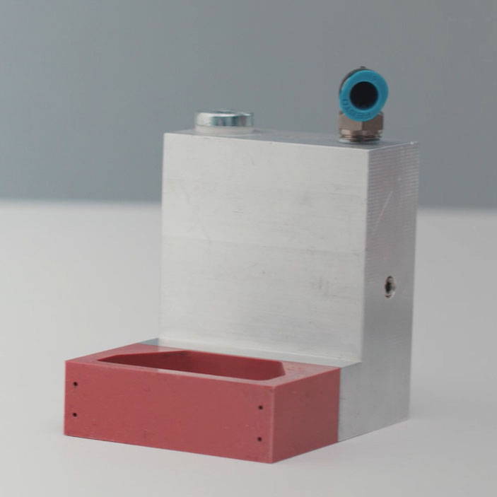 Aluminiumbauteil mit rotem Kunststoffelement und Anschluss für Druckluft. Ideal für industrielle Anwendungen.