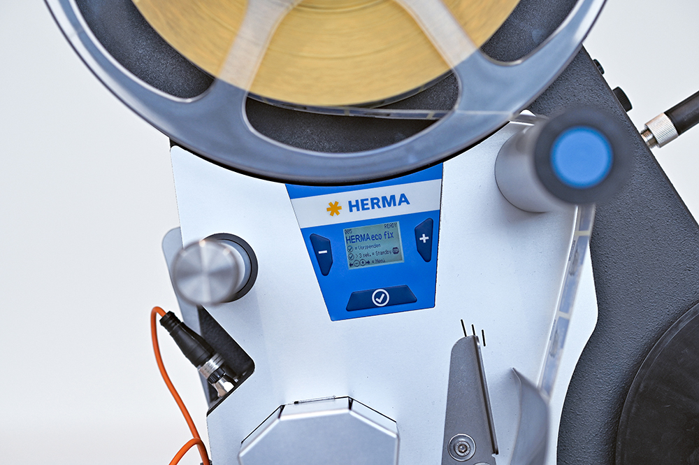 Ein Etikettiergerät mit einem digitalen Display und einer Rolle Etiketten. Die Steuerungselemente sind gut sichtbar.