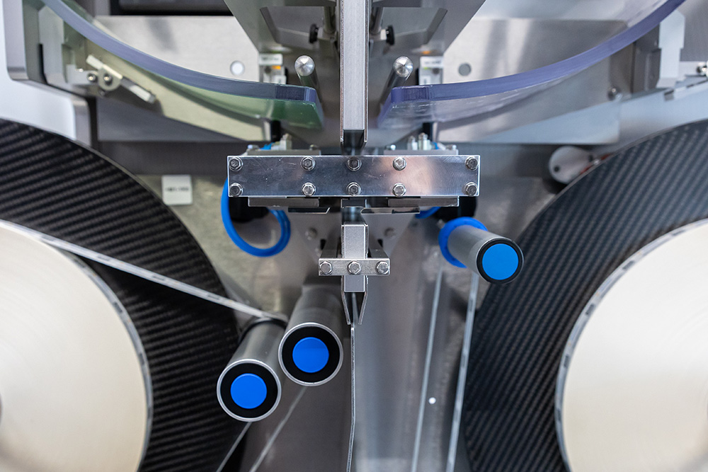 Maschine mit mehreren Rohren und blauen Griffen, die zur Verarbeitung von Materialien oder Produkten entwickelt wurde.