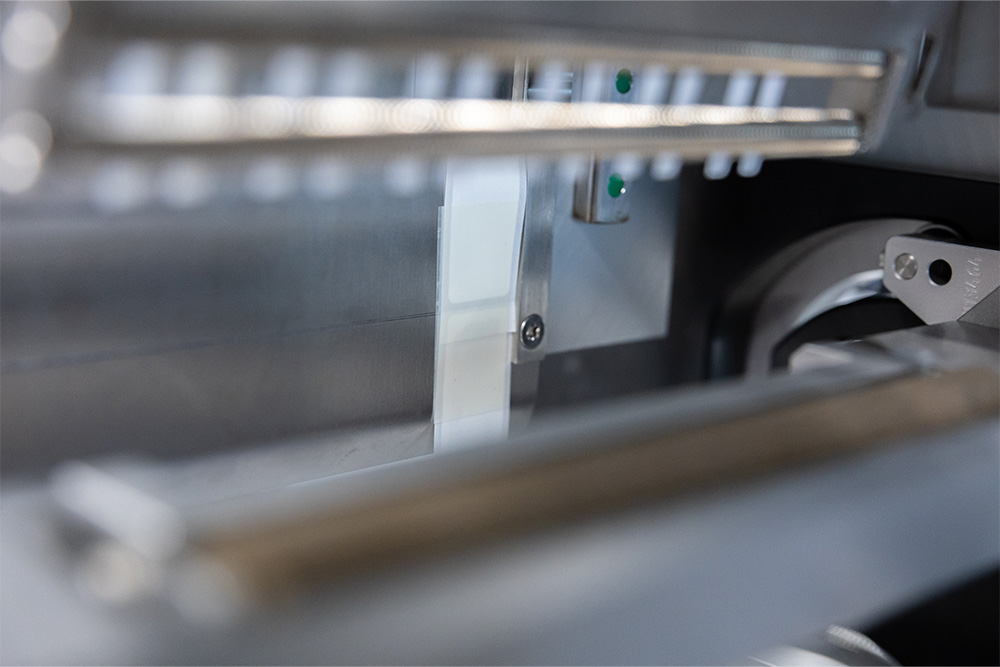 Ein Blick auf die Innenteile einer Maschine mit metallischen Komponenten und einem weißen Element, das in einem mechanischen System eingebaut ist.