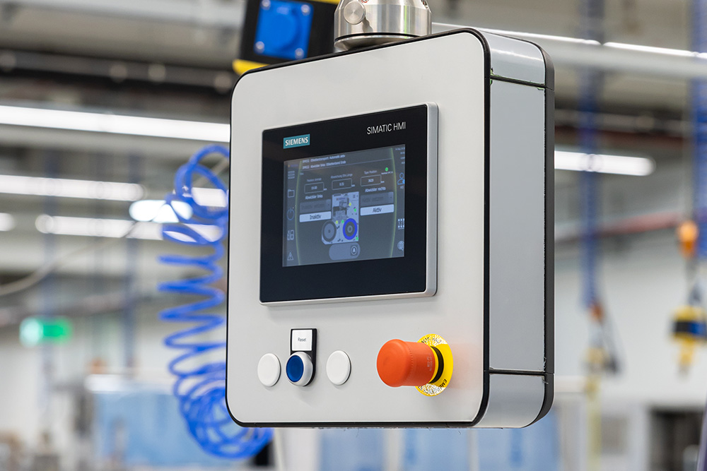 Touchscreen-Bedienfeld mit Steuerknöpfen, das zur Steuerung von Maschinen in einem industriellen Umfeld eingesetzt wird.