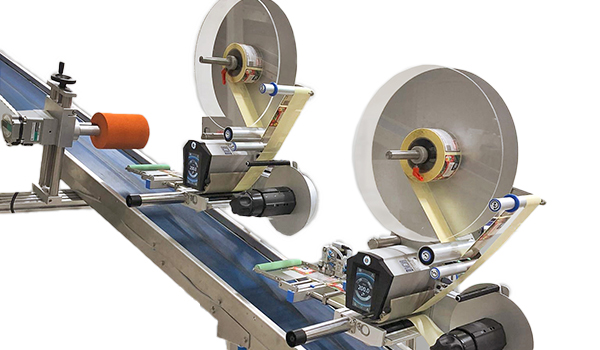 Eine Förderanlage mit zwei Rollen, die Etiketten auf Produkte aufbringt. Die Maschine ist mit Motoren und Steuerungselementen ausgestattet." 

(Note: The text is already in German and does not require translation. It is clear and fluent as it stands.)