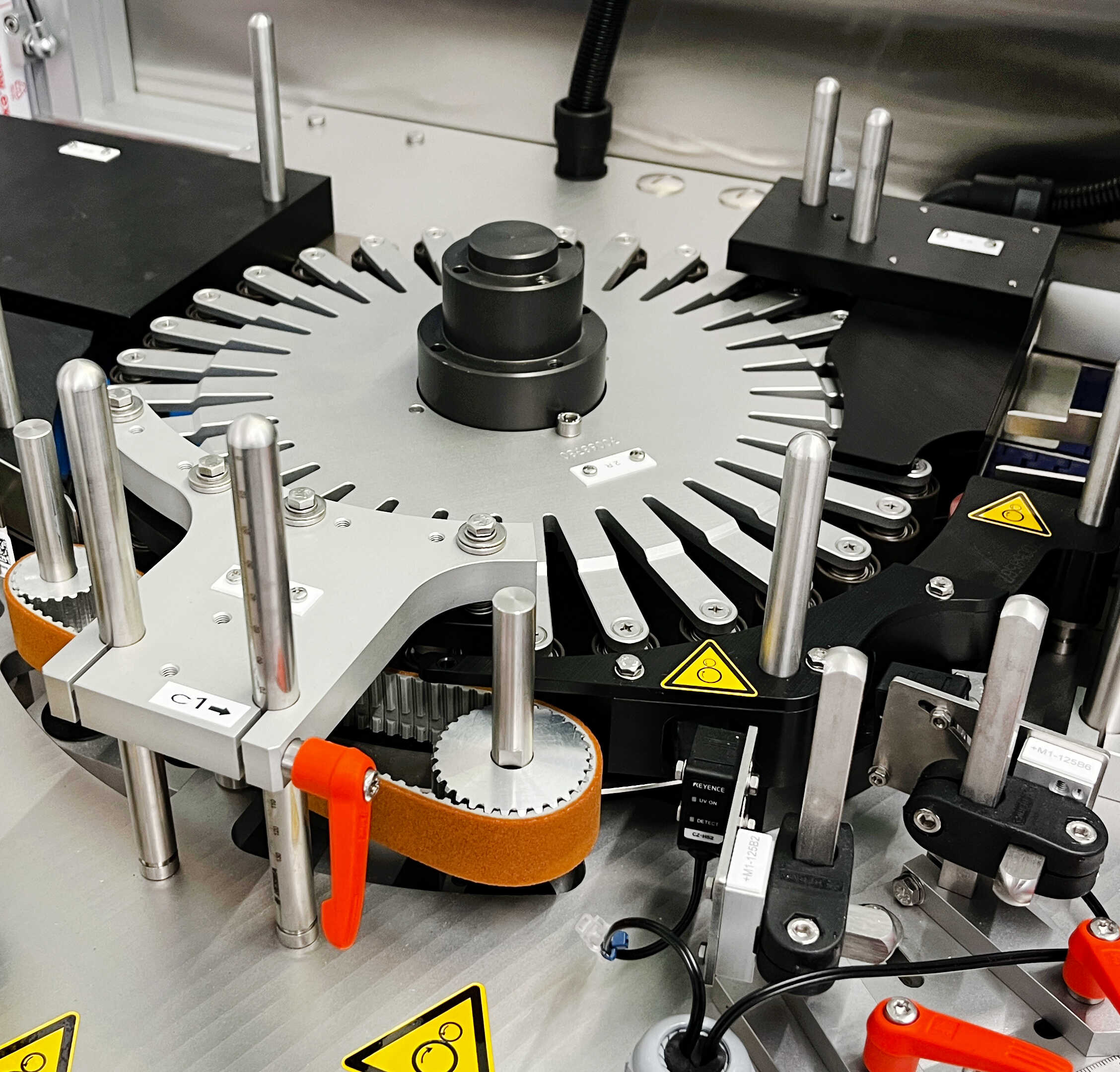 Maschine mit einem rotierenden Plattensystem, ausgestattet mit mehreren Halterungen und Sicherheitswarnungen.
