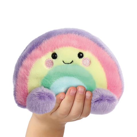 Eine Hand hält ein buntes, kuscheliges Regenbogen-Plüschtier mit einem lächelnden Gesicht und runden, farbigen Akzenten.