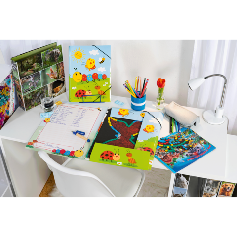 Bürotisch mit bunten Schulmaterialien, Notizheften, Stiften in einem Behälter und einer Blume in einer Vase.