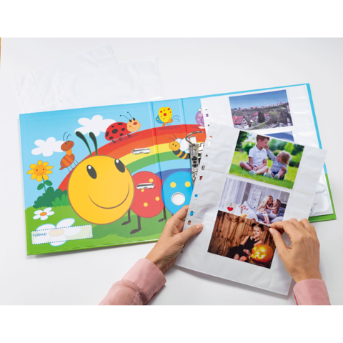 Ein offenes Bilderbuch mit bunten Illustrationen von Insekten und Blumen, daneben eine Person, die Fotos in einer transparenten Hülle betrachtet.