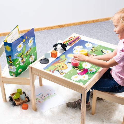 Ein Mädchen sitzt an einem Tisch und spielt mit bunten Spielzeugen und einem Puzzle, umgeben von einer fröhlichen, blühenden Landschaft.