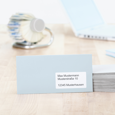 Blaue Kunststoffbox mit der Aufschrift "0134" und einem Etikett, daneben ein Notizblock und ein blauer Stift auf einem Tisch.