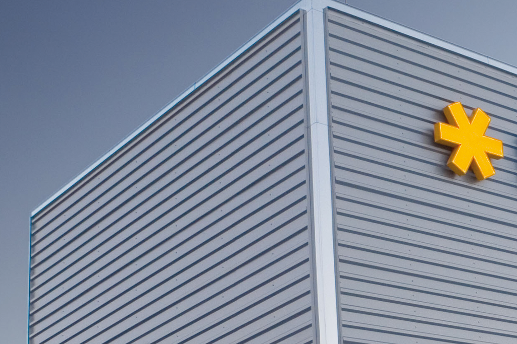 Fassade eines modernen Gebäudes mit dem Logo von HERMA in blauer Schrift und einem gelben Symbol.