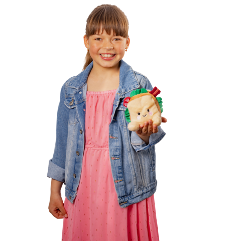 Ein Mädchen in einem rosa Kleid und einer Jeansjacke hält ein kuscheliges Stofftier in Form eines Tieres, das einen Hamburger hält.