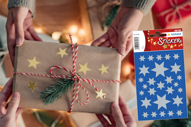 Geschenkverpackung mit goldenen Sternen, umgeben von Weihnachtsdekoration und zwei Rollen Geschenkpapier in Rot und Blau." 

(Note: The text is already in German and does not require translation. It is clear and fluent as it is.)
