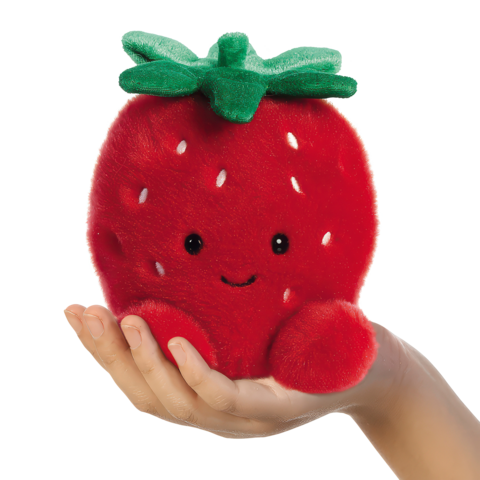 Eine Hand hält ein rotes, weiches Erdbeer-Plüschtier mit einem lächelnden Gesicht und grünen Blättern oben drauf.
