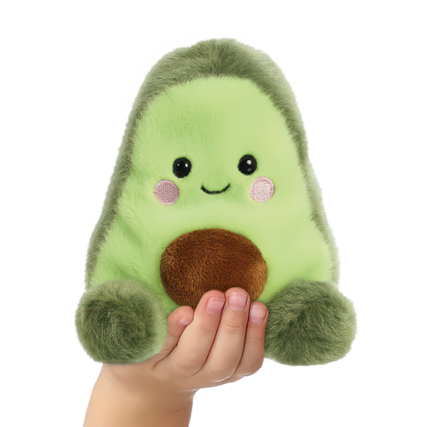 Eine handgehaltene, grüne Plüschavocado mit einem lächelnden Gesicht und einem braunen Kern.