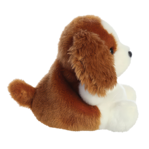 Ein sitzender Plüschhund mit braun-weißem Fell und einem runden Körper. Der Hund hat große, freundliche Augen und einen kleinen Schwanz.