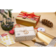 Geschenkverpackungen in Gold und Weiß mit Punkten, umgeben von Dekorationen wie Kerzen, einer Tannenzapfen und Geschenkband.