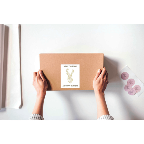Eine Person hält ein braunes Paket mit einem Aufkleber, der "Frohe Weihnachten und ein glückliches neues Jahr" zeigt.