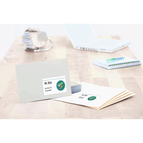 Ein Briefumschlag mit dem Namen "Mr. Bird" und einem Logo, daneben liegen mehrere leere Umschläge und ein Notizbuch auf einem Tisch.