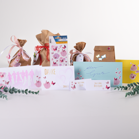 Geschenktüten und Karten in verschiedenen Farben und Designs, darunter eine "Danke"-Karte und eine "Alles Gute"-Karte, verziert mit Schmetterlingen.