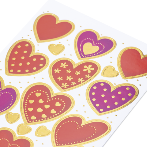 Bunte Herzaufkleber in verschiedenen Größen und Farben, umgeben von goldenen Akzenten auf einem weißen Hintergrund.