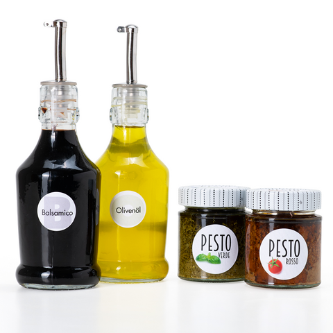 Fünf Glasbehälter mit verschiedenen Lebensmitteln: Mehl, Reis, Müsli, Pasta und Haferflocken, jeweils mit beschrifteten Etiketten.