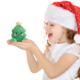 Ein Mädchen mit einem Weihnachtsmann-Hut hält ein grünes, lächelndes Plüschweihnachtsbaumspielzeug in den Händen.