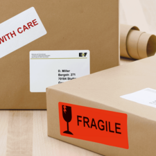 Paket mit einem Aufkleber "Vorsicht" und einem anderen Aufkleber "Zerbrechlich", adressiert an D. Miller in Stuttgart.