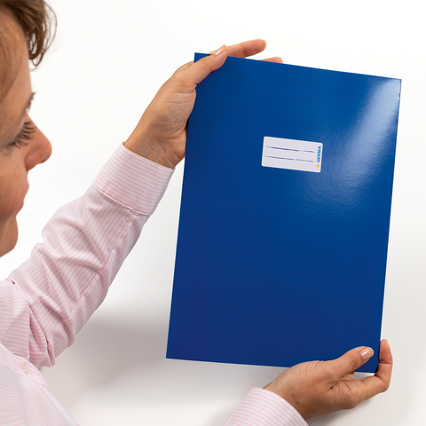 Eine Person hält eine blaue Mappe mit einem Aufkleber auf der Vorderseite in der Hand." 

(Note: The text is already in German and does not require translation. It is clear and fluent as it is.)