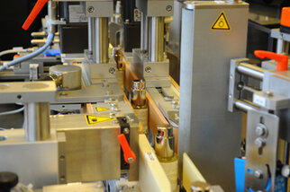 Automatisierte Maschinen zur Verarbeitung von Flaschen, mit verschiedenen mechanischen Komponenten und Sicherheitskennzeichnungen.