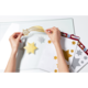 Hände platzieren goldene und silberne Glitzersterne auf einer transparenten Oberfläche, um eine Dekoration zu gestalten.