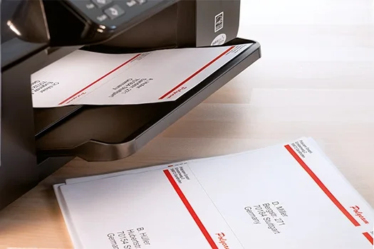 Drucker mit bedruckten Etikettenbögen auf Schreibtisch