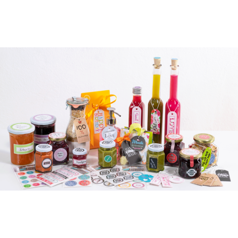 Eine Auswahl an verschiedenen Gläsern mit Marmelade, Ölen und Gewürzen, umgeben von bunten Etiketten und Verpackungen.