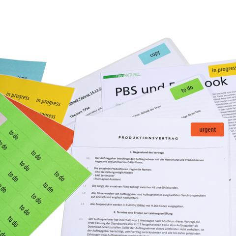 Eine Vielzahl von Dokumenten und Notizen, versehen mit bunten Haftnotizen, darunter ein Produktionsvertrag und Arbeitsanweisungen.