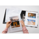 Eine Person hält Fotos in einer transparenten Hülle, während ein Fotoalbum mit weiteren Bildern im Hintergrund sichtbar ist.