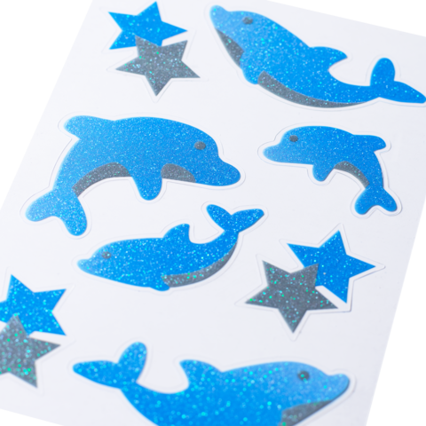 Blaue Glitzeraufkleber in Form von Delfinen und Sternen auf einem weißen Hintergrund.