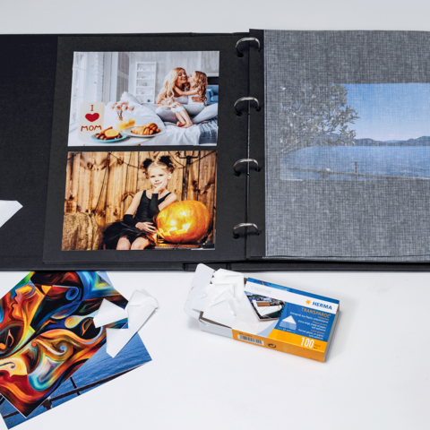 Ein Fotoalbum mit verschiedenen Bildern, darunter Porträts und Landschaften, sowie einige lose Fotokarten und eine Filmhülle.