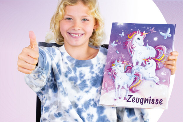 Ein Mädchen lächelt und zeigt den Daumen nach oben, während es einen bunten Ordner mit einem Einhorn-Motiv und leeren Seiten in der Hand hält.